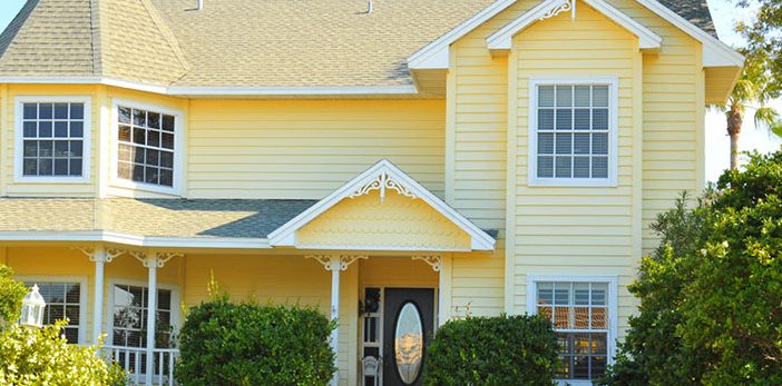 a tan two story house with a nice landscaped yard