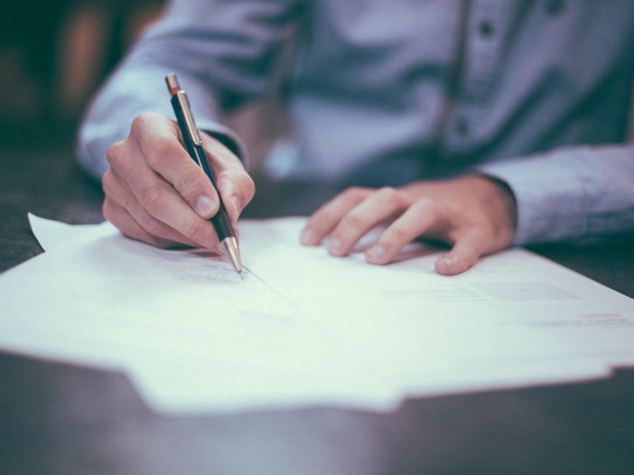 a person in blue shirt signing a dcocument