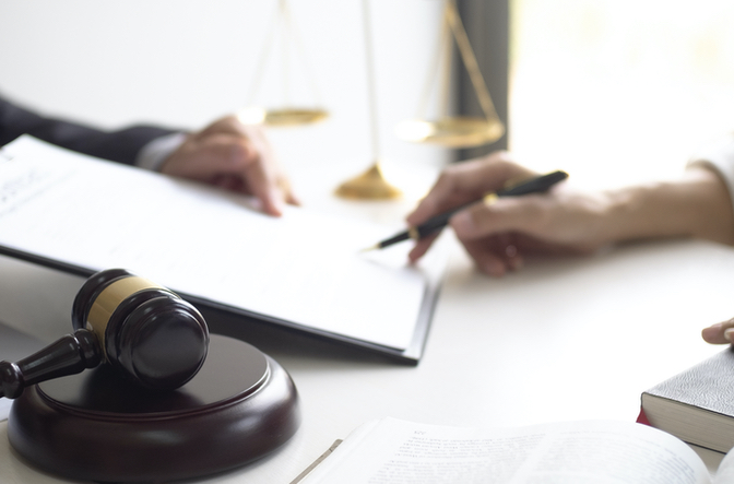 a persons hand with a pencil next to a document and gavel